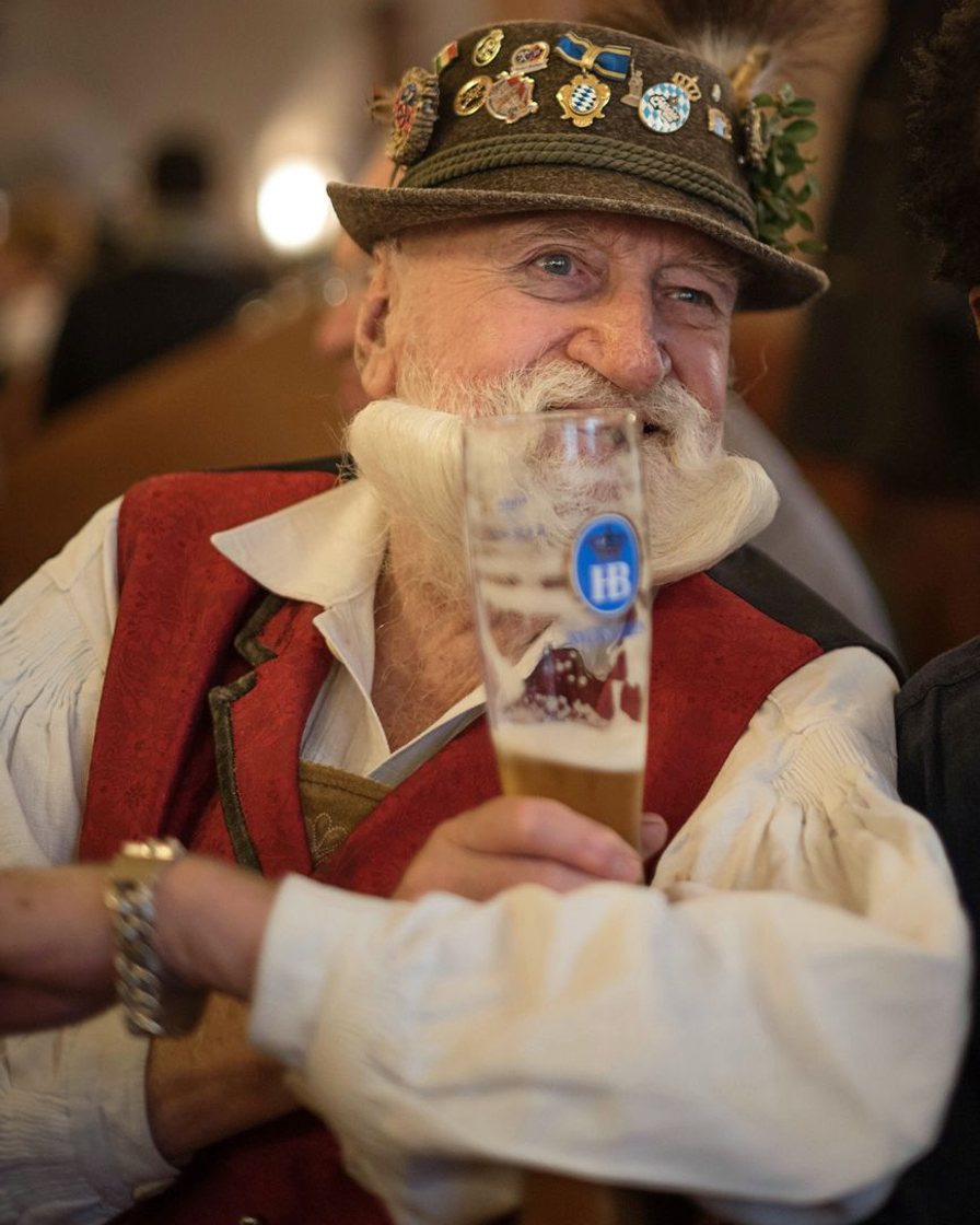 Gefüllter Maßkrug auf einem Biergartentisch vor Kastanienlaub