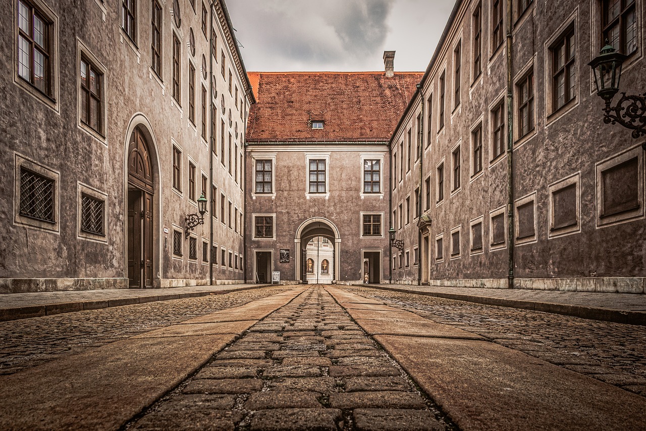 Kopfsteingepflasterte Gasse in der Münchner Altstadt zwischen hohen Wohnhäusern