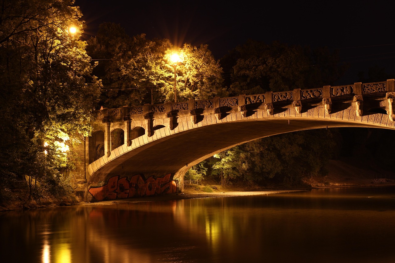 Die beleuchtete Maximiliansbrücke über der Isar bei Nacht