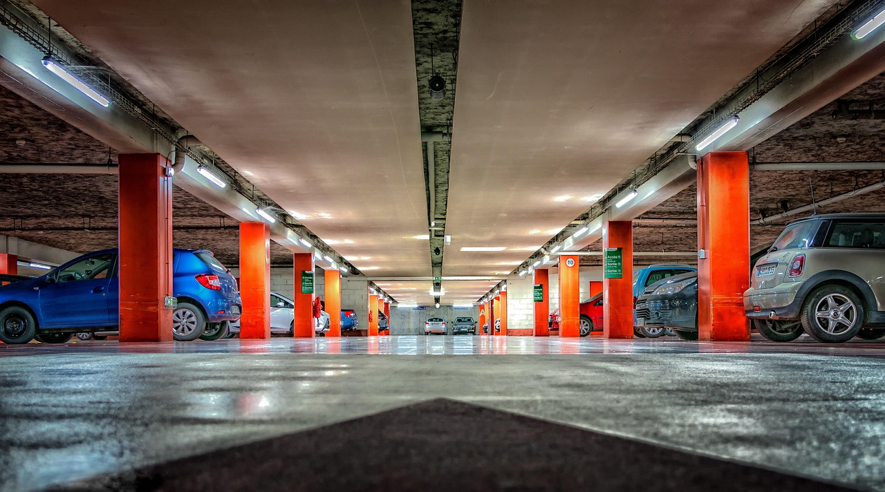 Leere Parkebene mit orangefarbenen Stützen und Leuchtstoffröhren, Blick über den Fahrbahnpfeil