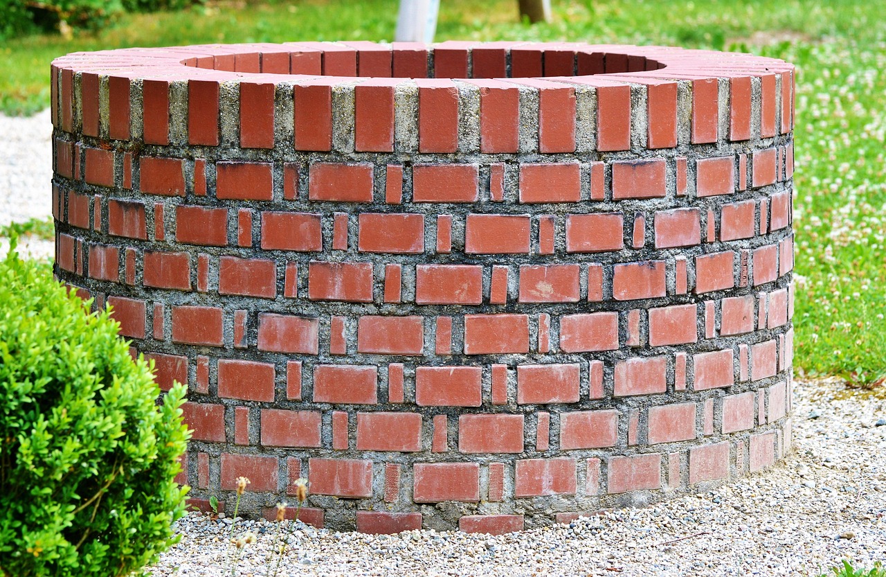 Steinerner Trinkbrunnen an einer Klinkerwand mit laufendem Wasserstrahl